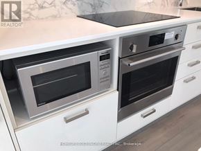 Vaughan (Vaughan Corporate Centre) condo for rent - A modern kitchen with white cabinets and a marble backsplash.