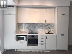 Vaughan (Vaughan Corporate Centre) condo for rent - A kitchen with white cabinets and a marble backsplash.