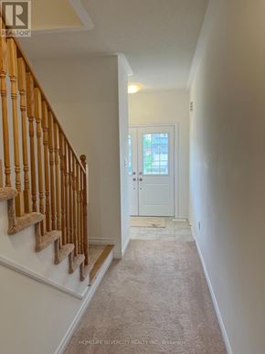 Southgate apartment for rent - A hallway with a carpeted floor, a white door, and a wooden staircase with a beige runner.
