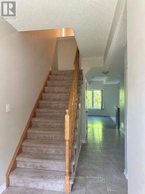 Wasaga Beach townhouse for rent - A staircase with a light brown carpet and wooden balusters.