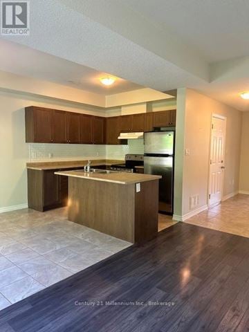 Wasaga Beach townhouse for rent - A kitchen with wooden cabinets and a black refrigerator.