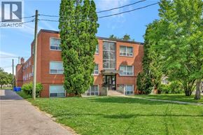 Hamilton condo for rent - A red brick building with a green lawn in front.