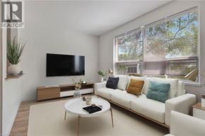 Hamilton condo for rent - A living room with a white couch, a coffee table, and a flat screen TV mounted on the wall.