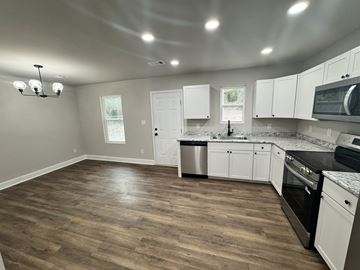 Warner Robins apartment for rent - A kitchen with white cabinets and a wooden floor.