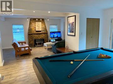 Burnaby apartment for rent - A pool table is in the middle of a living room with a fireplace and a TV.