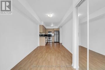 Markham (Greensborough) townhouse for rent - A spacious room with wooden flooring and white walls, leading to a kitchen area.