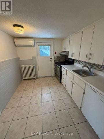 Toronto (Junction Area) multi-family for rent - A kitchen with white cabinets and a tiled floor.