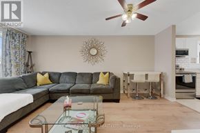 Barrie (Georgian Drive) apartment for rent - A living room with a grey sofa, a glass coffee table, and a sunburst mirror on the wall.