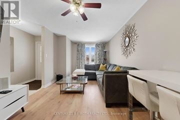Barrie (Georgian Drive) apartment for rent - A living room with a brown couch and a ceiling fan.