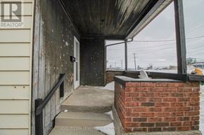 Port Colborne (East Village) multi-family for rent - A wooden porch with a brick pillar and a metal railing.