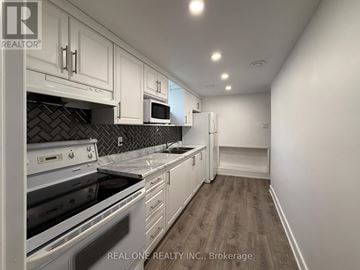 Mississauga (Erindale) apartment for rent - A kitchen with white cabinets and a black tile backsplash.