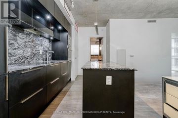 Toronto (Waterfront Communities) condo for rent - A kitchen with a black counter top and wooden floors.