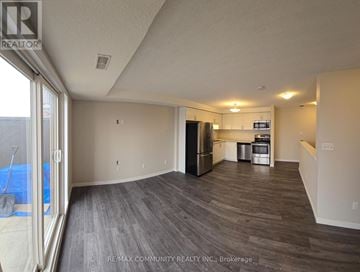 Kitchener townhouse for rent - A spacious room with a kitchenette and a view of a pool through a glass door.