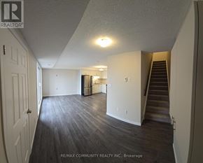 Kitchener townhouse for rent - A spacious room with wooden flooring and a staircase leading to another level.