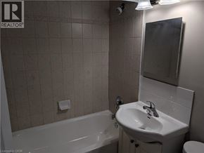 Hamilton condo for rent - A bathroom with a white tub, sink, and toilet.