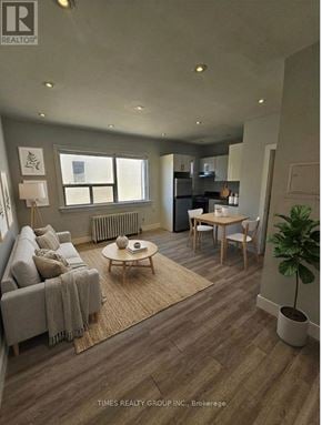 Toronto (Bedford Park-Nortown) multi-family for rent - A well-lit living room with a grey sofa, a coffee table, and a dining table with chairs.