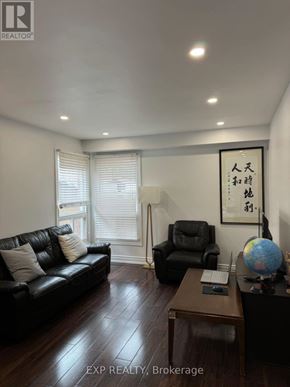 Toronto (Milliken) apartment for rent - A living room with a black couch, a black chair, and a wooden coffee table.