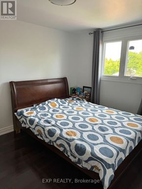 Toronto (Milliken) apartment for rent - A bed with a blue and yellow patterned comforter sits in a room with a window.