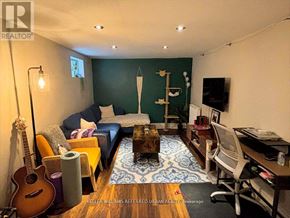 Toronto (Danforth Village-East York) apartment for rent - A living room with a guitar, a couch, a coffee table, and a TV.
