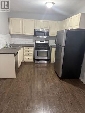 Welland (Welland Downtown) multi-family for rent - A kitchen with a black fridge and stove top oven.
