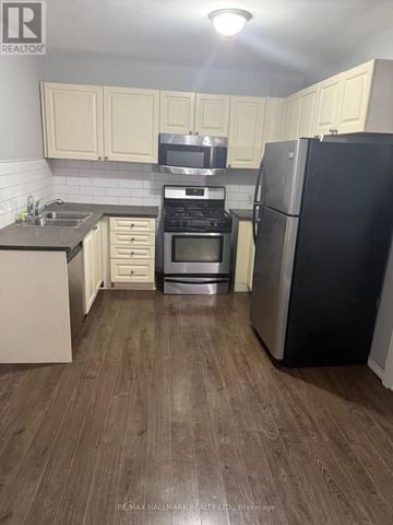 Welland (Welland Downtown) multi-family for rent - A kitchen with a black fridge and stove top oven.