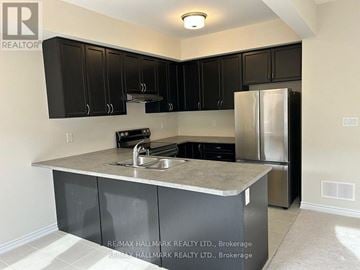 Brantford townhouse for rent - A kitchen with black cabinets and a stainless steel refrigerator.