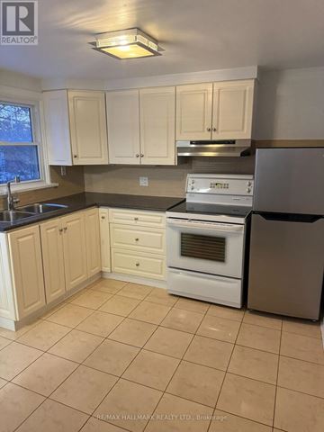 St. Catharines (Downtown) multi-family for rent - A kitchen with white cabinets and a black fridge.