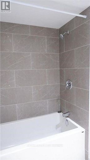 Toronto (Morningside) apartment for rent - A white bathtub is in a bathroom with grey tiles.
