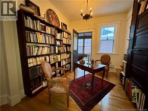 Moncton apartment for rent - A room with a bookshelf filled with books and a chair in front of it.