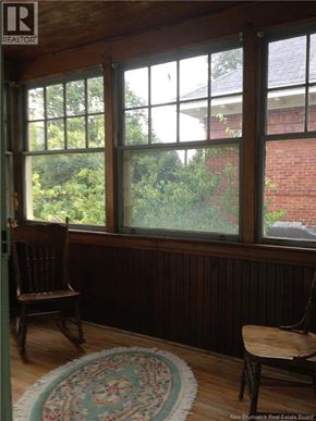 Moncton apartment for rent - A room with a large window and a wooden chair.