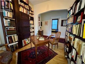 Moncton apartment for rent - A room with a table, chairs, and bookshelves filled with books.