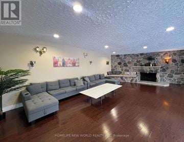 Whitchurch-Stouffville apartment for rent - A living room with a grey sofa and a stone fireplace.