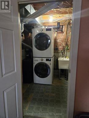 Kitchener townhouse for rent - A white dryer and washer are in a small, cluttered laundry room.