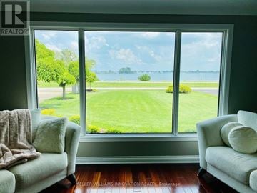 Fort Erie (Central) apartment for rent - A living room with two couches and a view of a green field and water through the windows.