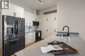 Kingston (City Northwest) condo for rent - A modern kitchen with a stainless steel refrigerator and white cabinets.