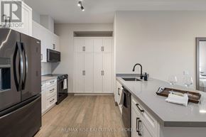 Kingston (City Northwest) condo for rent - A modern kitchen with a refrigerator, microwave, oven, and cabinets.