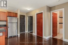 Kingston (East Gardiners Rd) condo for rent - A kitchen with a refrigerator, cabinets, and a door leading to a bathroom.