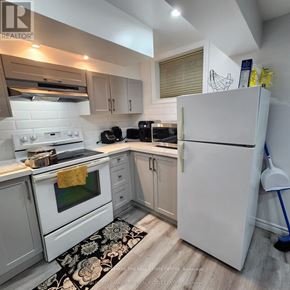 Barrie (Grove East) apartment for rent - A kitchen with white appliances and a black and white rug on the floor.