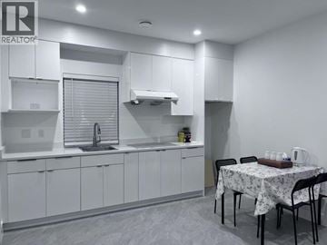 Vancouver apartment for rent - A kitchen with white cabinets and a table set for two.