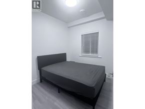 Vancouver apartment for rent - A bedroom with a bed, window, and a light on the ceiling.