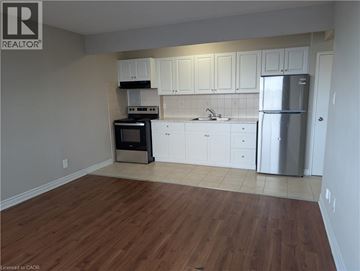 Hamilton condo for rent - A kitchen with white cabinets and a wooden floor.
