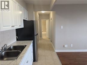 Hamilton condo for rent - A kitchen with white cabinets and a black refrigerator.