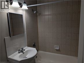 Hamilton condo for rent - A bathroom with a sink, mirror, and bathtub.