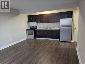 Hamilton condo for rent - A kitchen with dark wood cabinets and a white fridge.