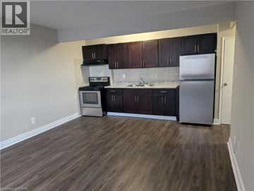 Hamilton condo for rent - A kitchen with dark wood cabinets and a white fridge.