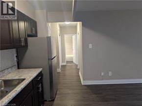 Hamilton condo for rent - A kitchen with dark wood cabinets and a stainless steel refrigerator.