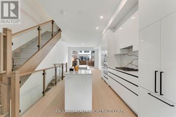 Mississauga (Port Credit) townhouse for rent - A modern kitchen with white cabinets and a wooden staircase.