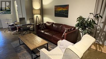 Toronto (Regent Park) condo for rent - A living room with a brown leather couch and a wooden coffee table.