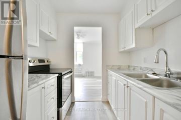 Barrie (Wellington) multi-family for rent - A kitchen with white cabinets and a marble countertop.