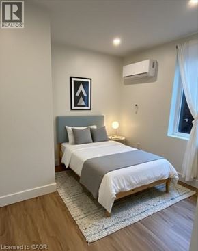 Hamilton apartment for rent - A bedroom with a bed, pillows, a nightstand, and a window.